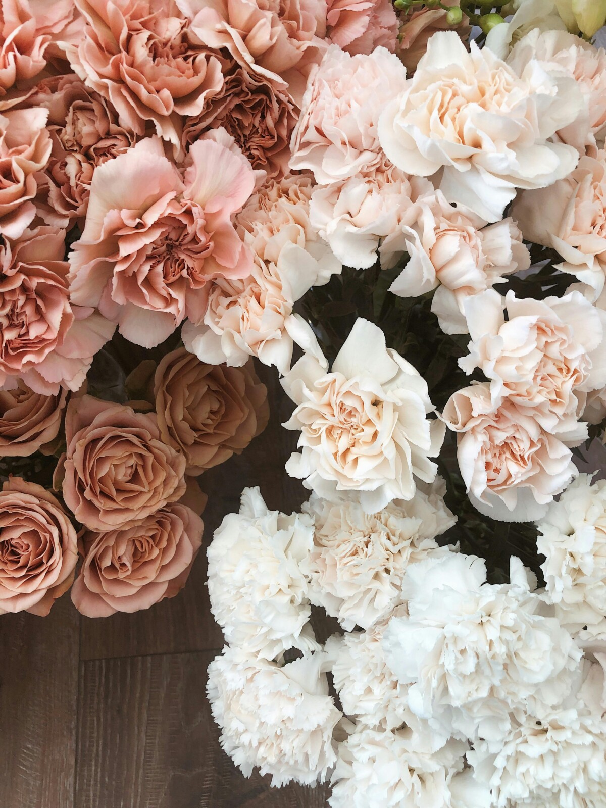 A delicate blend of pastel pink and white roses and carnations arranged elegantly.